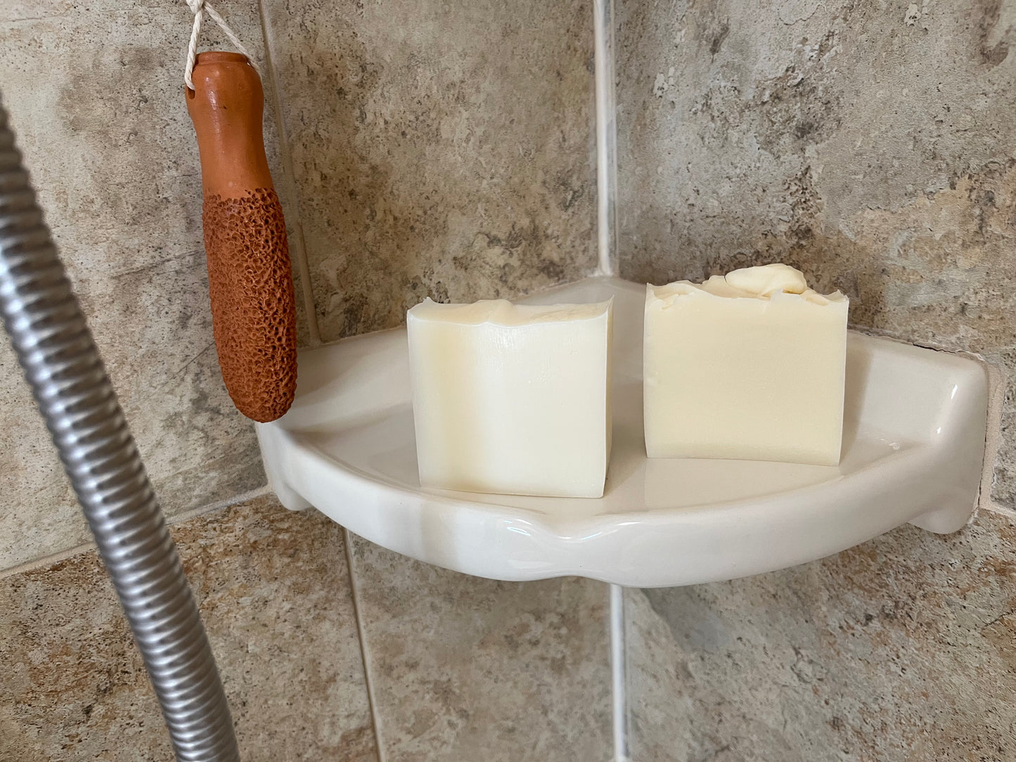 Corner soap dish with one vegan and one tallow bar of soap in a shower setting